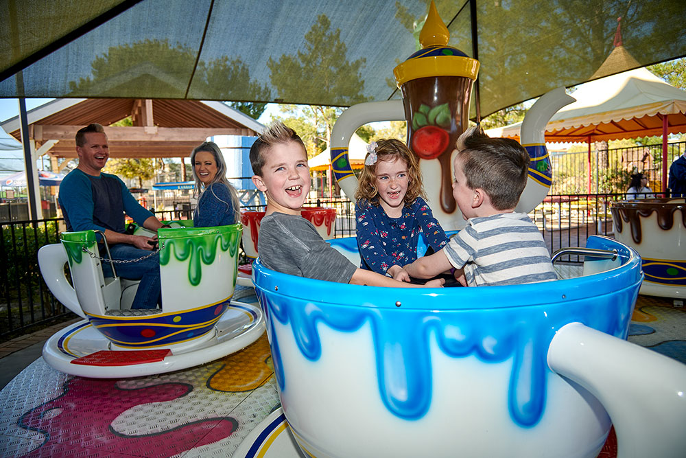 Kids on spinning teacup kiddie ride at Temecula outdoor attraction