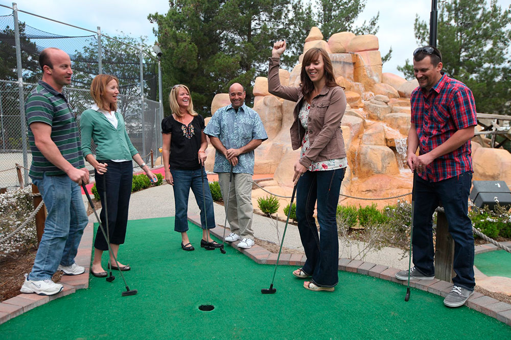 Adults enjoying a round of mini golf at Mulligan as part of the golf group package within the group packages options.