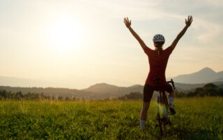 Woman on a racing bike celebrating with arms raised