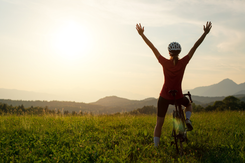 Woman on a racing bike celebrating with arms raised