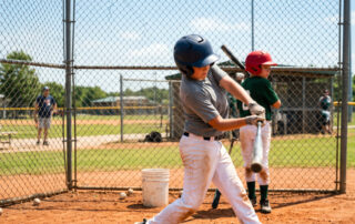 Young baseball players wearing helmets practising swing inside chain-link batting cage youth editorial